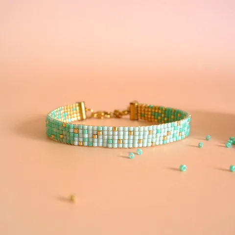 Bracelet en perles Miyuki turquoise, blanches et dorées sur fond pêche