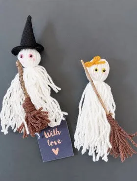 Deux fantômes en pompons de laine blanche, l’un en sorcière, avec leurs balais