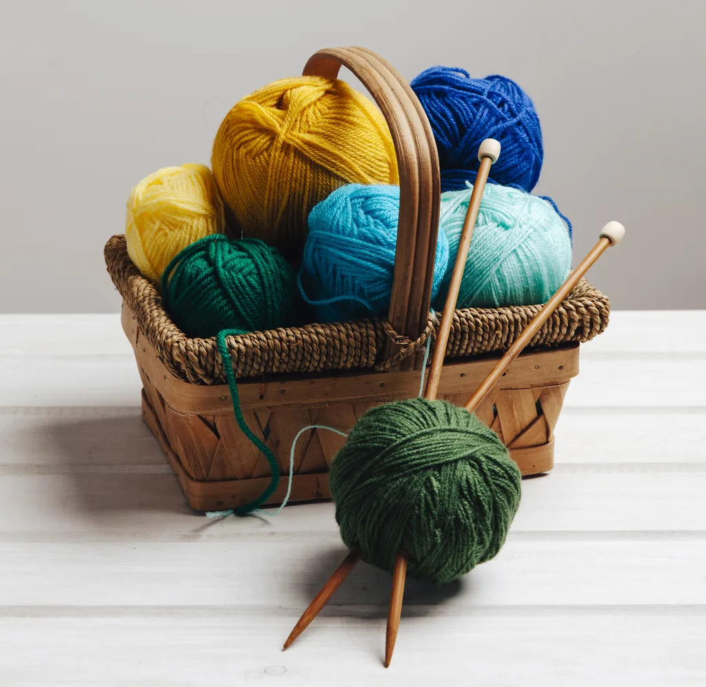 Panier de pelotes de laine colorées et aiguilles à tricoter en bois