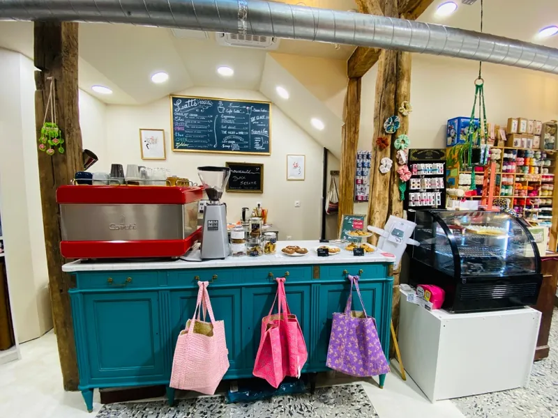 Le bar du café : la machine à expresso rouge, l’ardoise des lattes et les sacs en tissu suspendus au buffet bleu