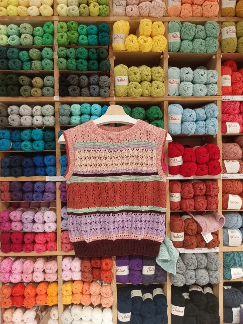 Un gilet tricoté à rayures devant le mur de pelotes
