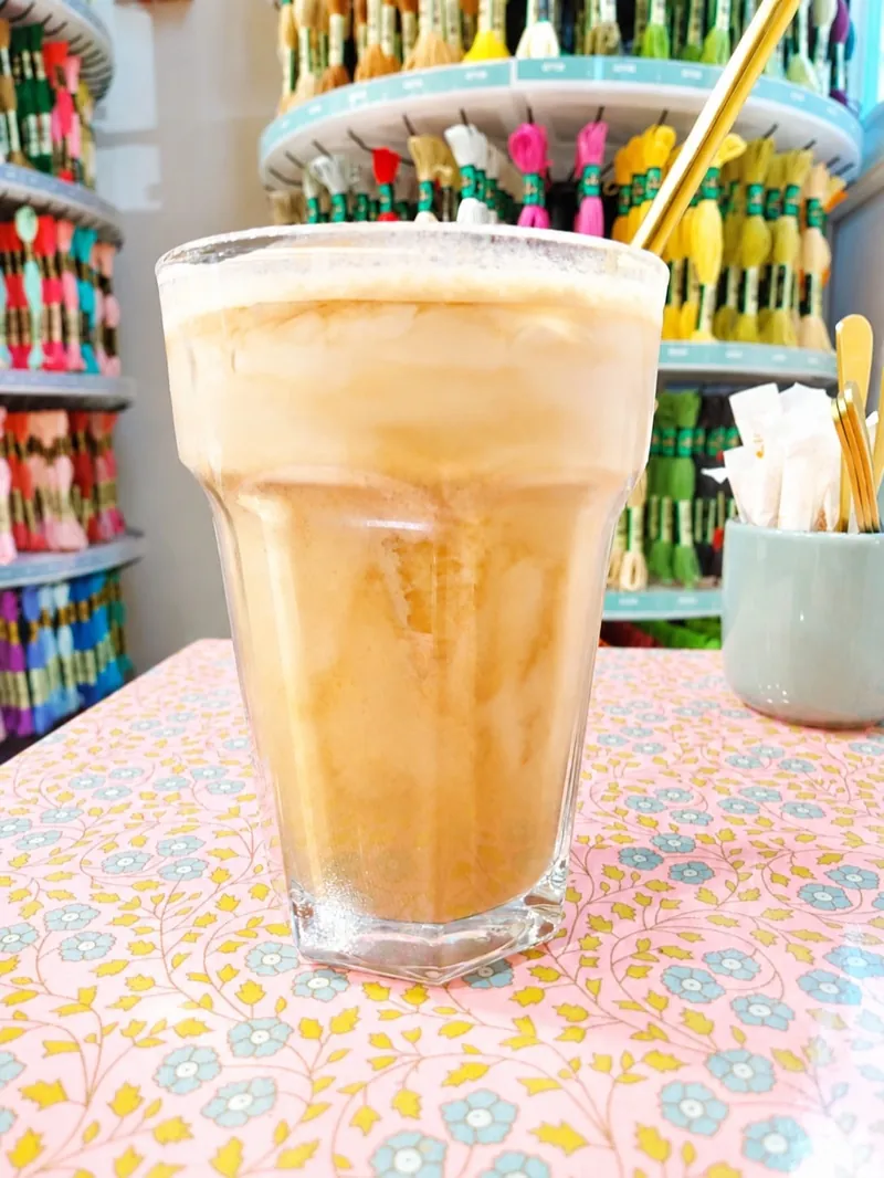 Un latte glacé posé sur une nappe fleurie, devant le mur de rubans