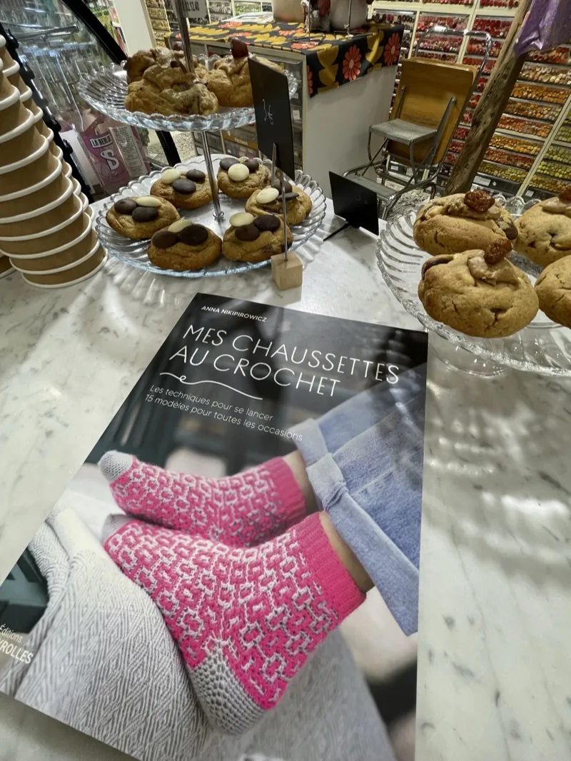 Les pâtisseries du jour sur le comptoir, près des chaussettes au crochet