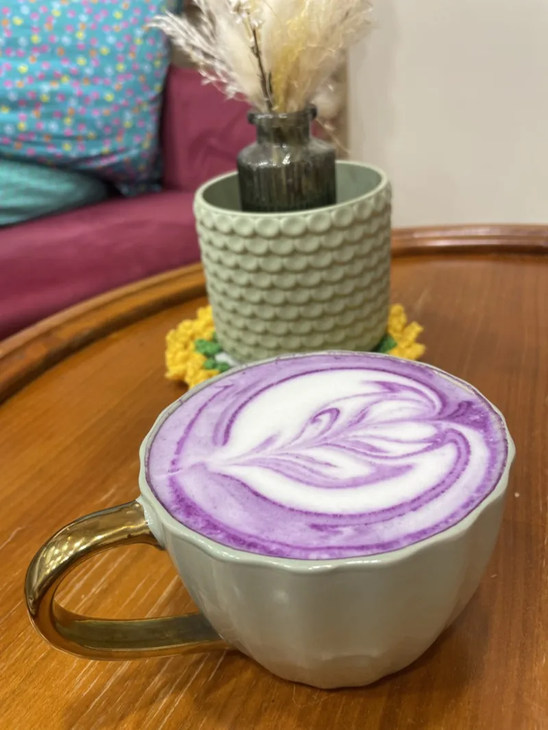 Un Purple latte à la mousse violette, servi dans une tasse en céramique